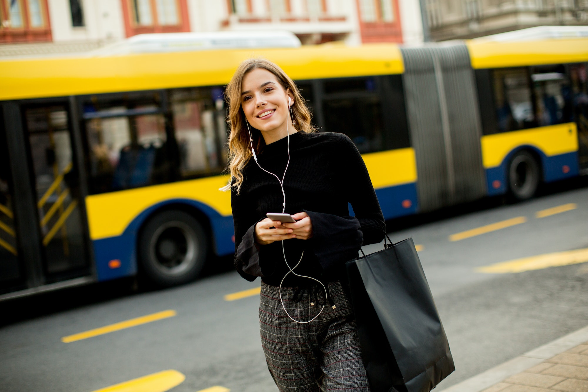 Young woman waiting for taxi or bus on the street in the city